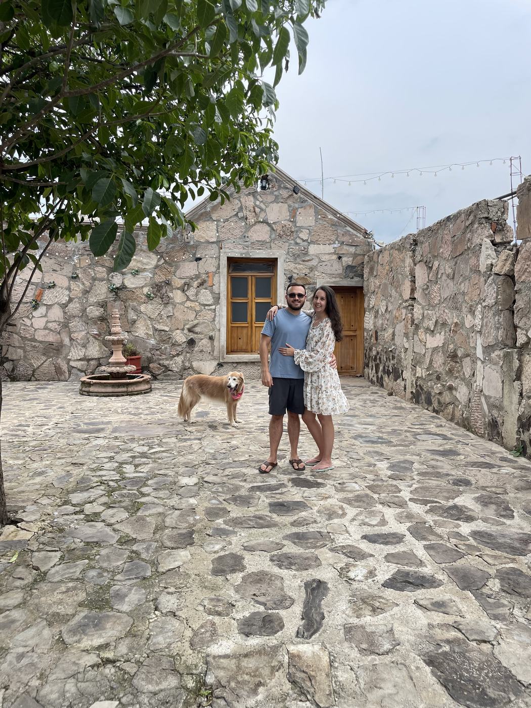Justin and Amanda with their dog in a cobblestone Mexican courtyard